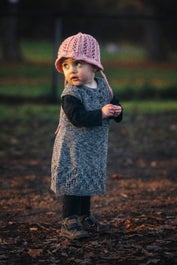 Lilja – babyklänning med hålmönster och knäppning fram eller bak